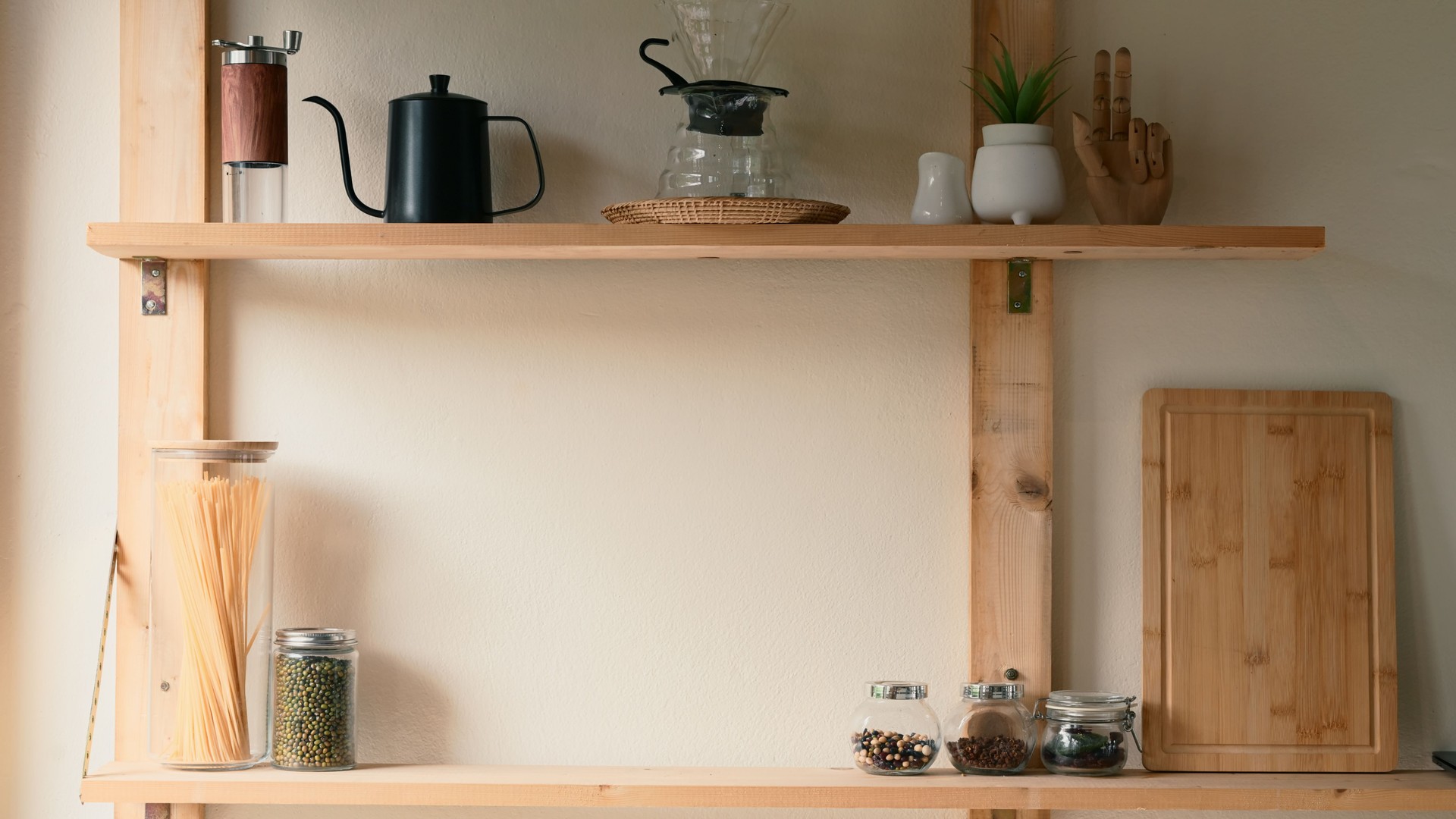 Minimalist wooden kitchen shelf with jars of pasta, legumes, spices, and stylish coffee accessories